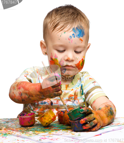 Image of Little boy is playing with paints