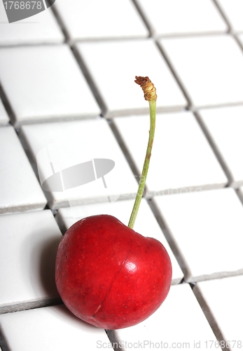 Image of isolated cherry on white tiles