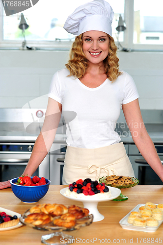 Image of Female chef posing in uniform inside kitchen