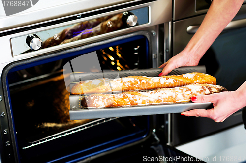 Image of Hands of a woman holding hot baguette