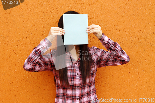 Image of Asian woman using book to cover face