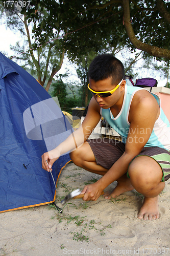 Image of Asian man set up tent in camping