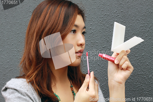 Image of Asian woman doing make-up