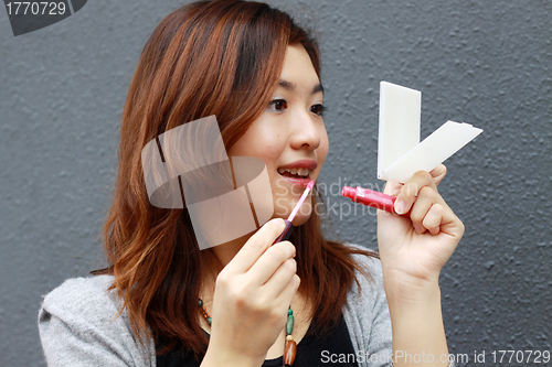 Image of Asian woman doing make-up