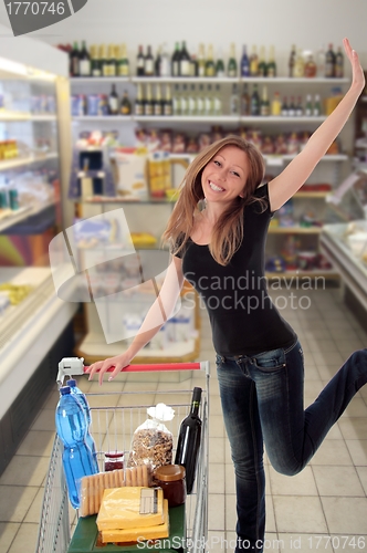 Image of Happy woman jumping in a supermarket