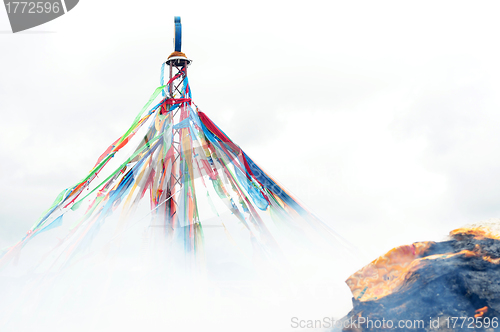 Image of Tibetan prayer flags and mani rock in the smoke