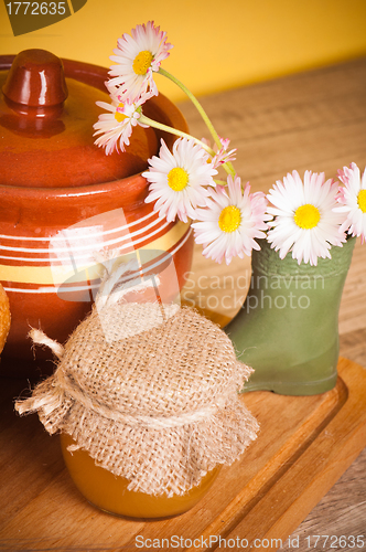 Image of Still life with honey, flowers and pot 