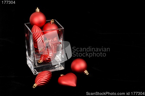 Image of Red Christmas ornaments in and around a glass vase