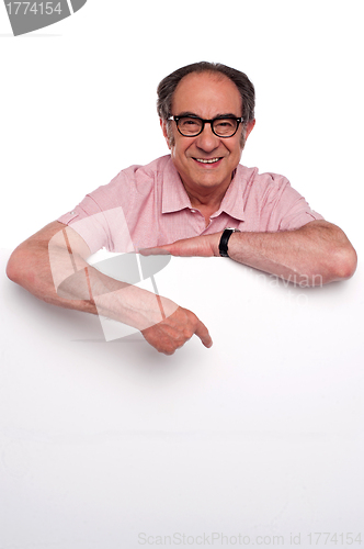 Image of Happy old man pointing at blank billboard