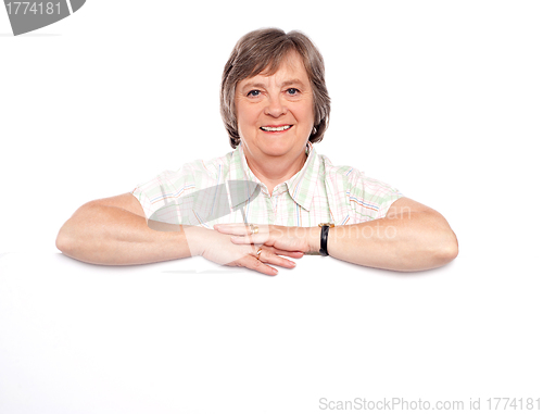 Image of Aged woman standing behind blank billboard