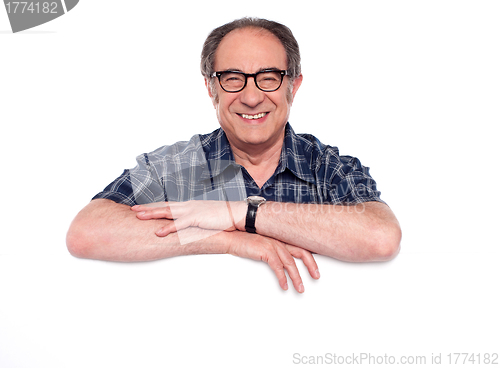 Image of Smiling aged man posing with blank billboard