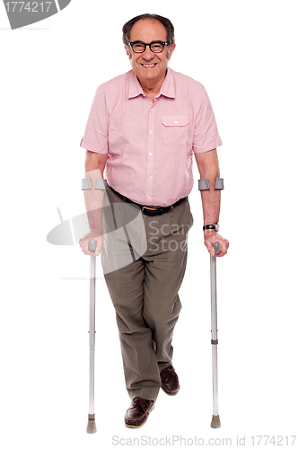 Image of Smiling senior man walking with two crutches