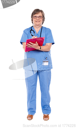 Image of Senior female doctor writing on clipboard