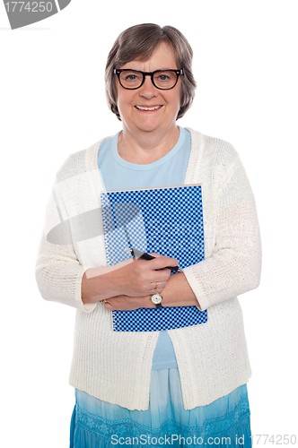 Image of Happy aged woman holding notebook and pen