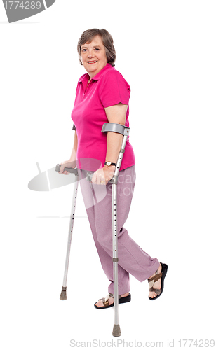 Image of Smiling senior woman walking with crutches