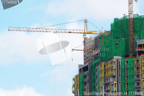 Image of Building crane and building under construction against blue sky 