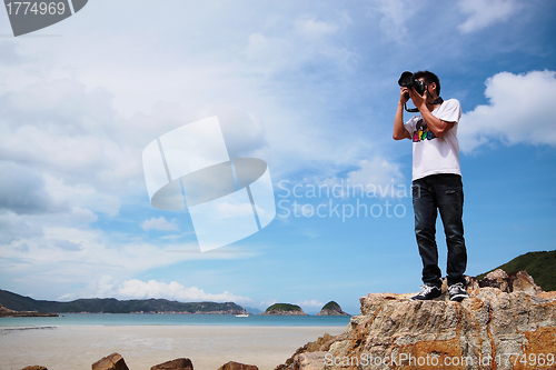 Image of Portrait of a young man standing on a beach with a camera 