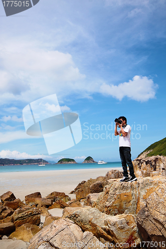 Image of Portrait of a young man standing on a beach with a camera 