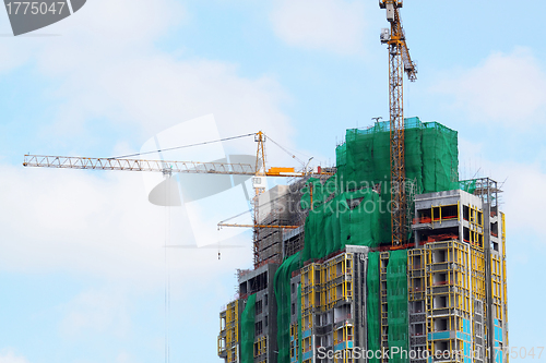 Image of Building crane and building under construction against blue sky 