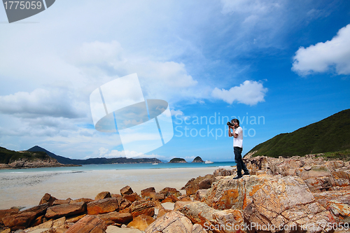 Image of Portrait of a young man standing on a beach with a camera 