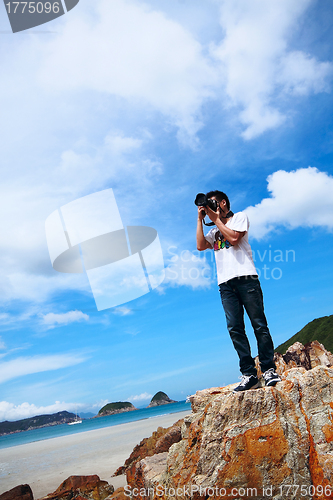 Image of Portrait of a young man standing on a beach with a camera 