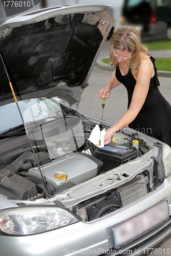 Image of Woman checking engine oil level