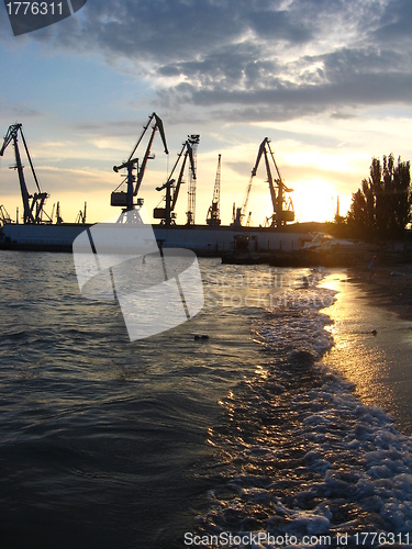 Image of everning sea with hoisting crane in the seaport