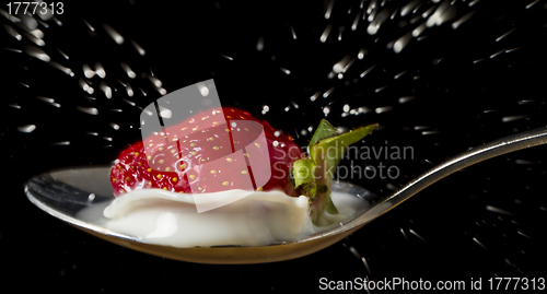 Image of red, ripe strawberry falling in spoon with milk