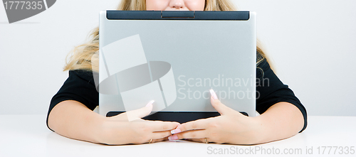 Image of The girl hides behind an laptop