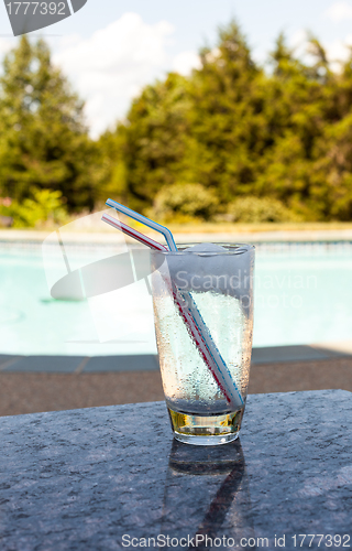 Image of Glass of water with ice cubes on side of pool