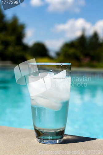 Image of Glass of water with ice cubes on side of pool