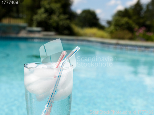 Image of Glass of water with ice cubes on side of pool