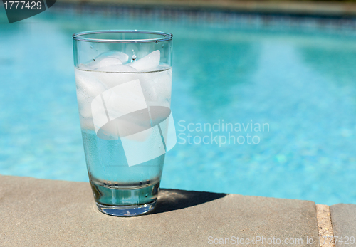 Image of Glass of water with ice cubes on side of pool