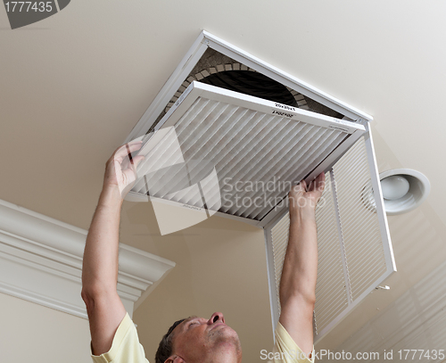 Image of Senior man opening air conditioning filter in ceiling