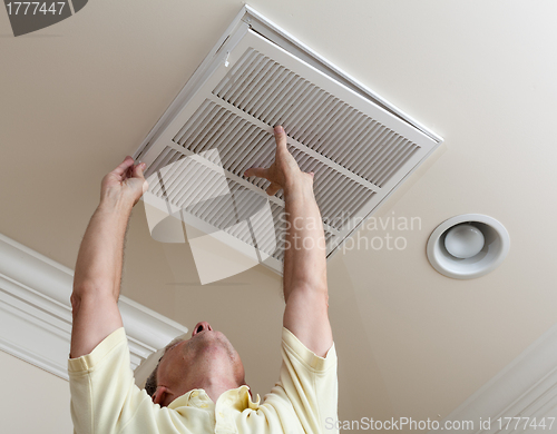 Image of Senior man opening air conditioning filter in ceiling