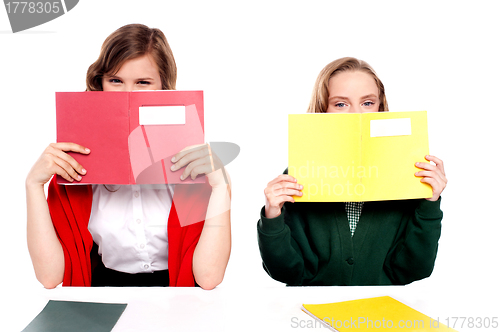 Image of Naughty schoolgirls hiding behind the book