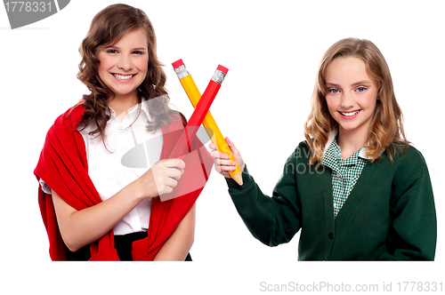 Image of Smiling teenagers making cross sign with pencil