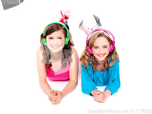 Image of Two beautiful girls lying on floor wearing headphones