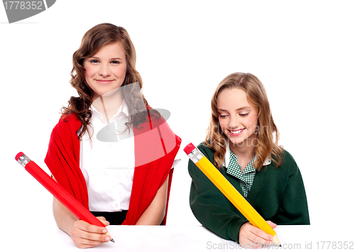 Image of Cheerful girls writing with pencil on surface