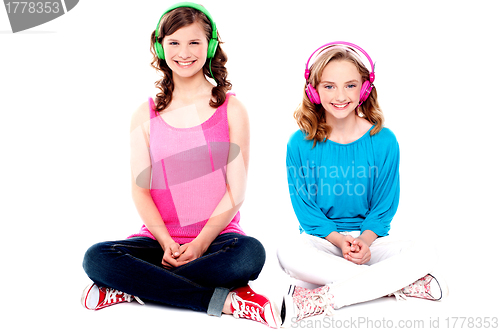 Image of Teenage friends sitting on floor listening music