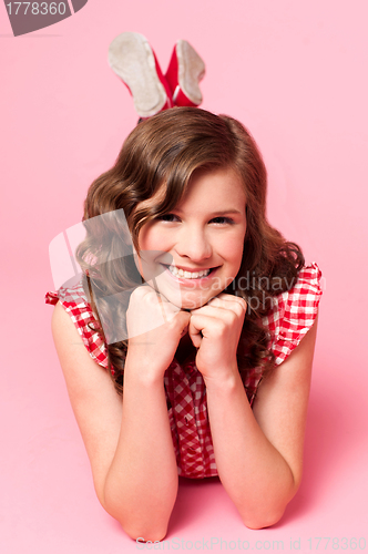 Image of Happy young girl lying on floor. Hands on chin