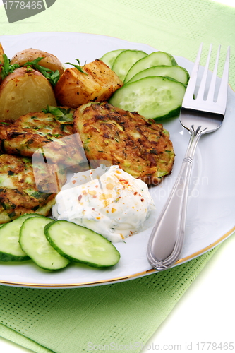 Image of Zucchini fritters,garnish and sour cream sauce. 