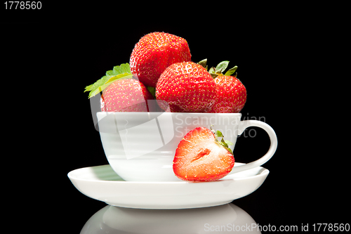Image of red strawberry in white cup on a black background