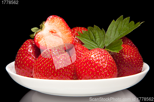 Image of white saucer with red strawberr on a black background