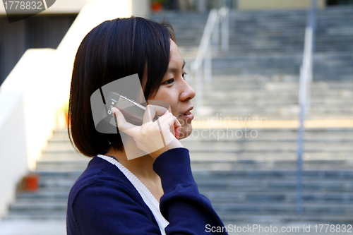 Image of Asian woman using mobile phone and talking