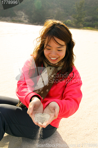 Image of Woman using sand to make heart by her hands 