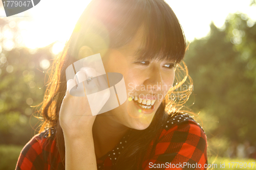 Image of Asian woman smiling under sunshine