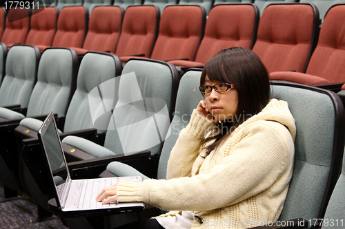 Image of Asian student studying in lecture hall with laptop