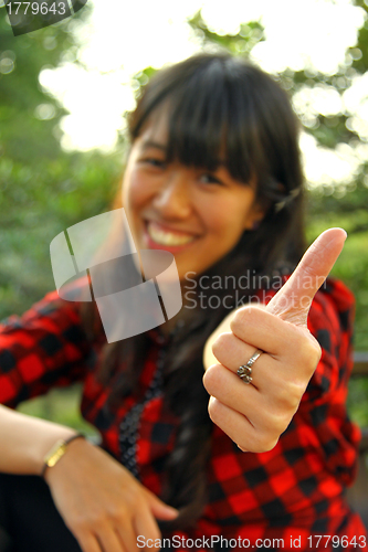 Image of Asian woman thumbs up outdoor
