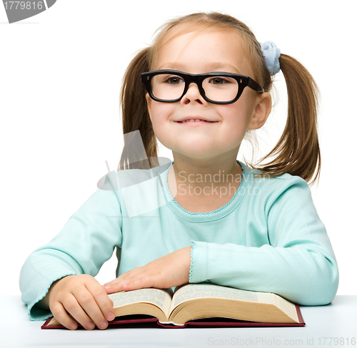 Image of Happy little girl with book wearing black glasses
